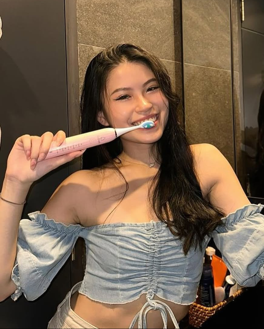 Woman holding a toothbrush in a bathroom setting