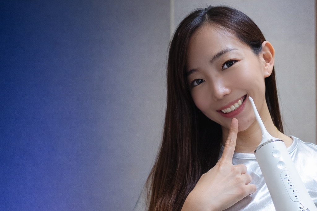 Woman holding a white electronic device, possibly a dental tool, with a blurred background